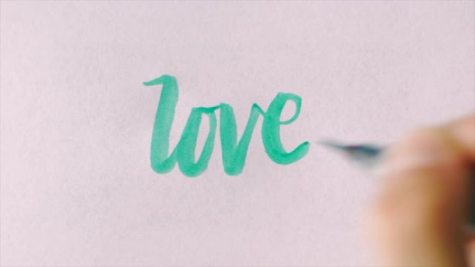 用草书的绿色书法笔在白纸上手写爱情