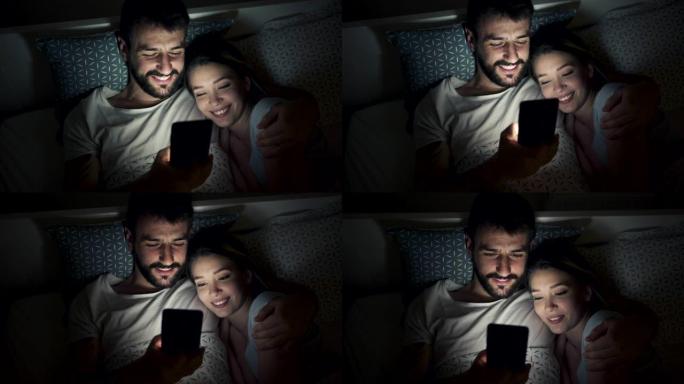 可爱的情侣躺在床上看手机好玩的东西