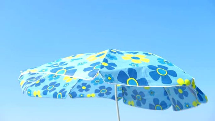 遮阳伞在蓝天下在沙滩上轻风移动
