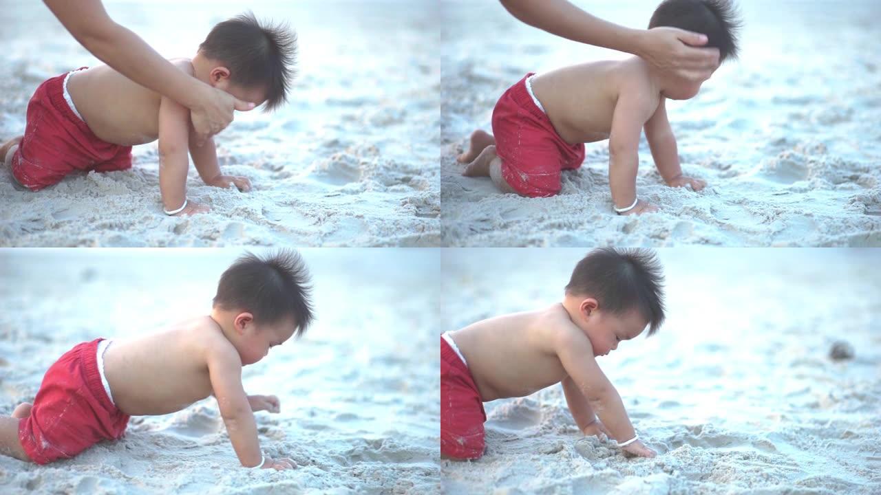 可爱的蹒跚学步的男孩在阳光明媚的夏日在沙滩上爬行。