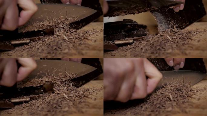 厨房板上切碎的黑巧克力。烘烤时切碎一块巧克力。慢动作。特写。在木制桌子上的砧板上切碎巧克力。特写。