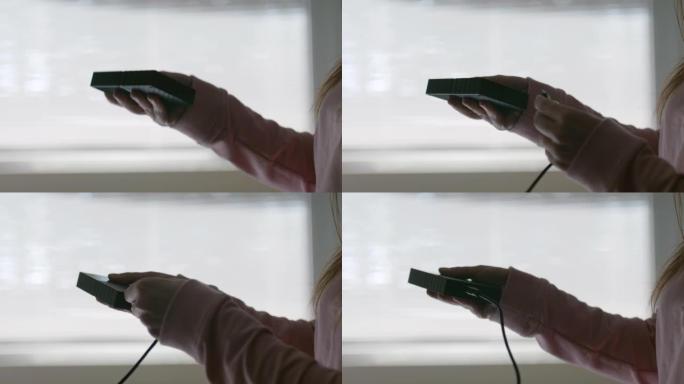 女人的手插入USB电缆以连接外部硬盘驱动器和智能手机。