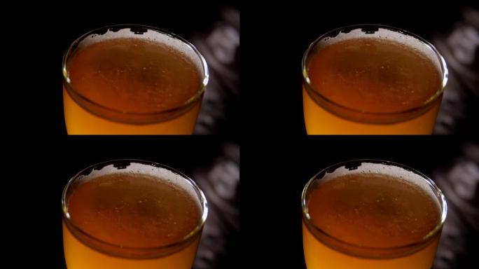 一杯啤酒的特写镜头，泡沫在黑暗中的木制背景上旋转