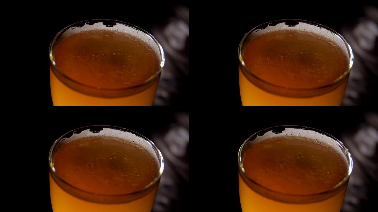 一杯啤酒的特写镜头，泡沫在黑暗中的木制背景上旋转
