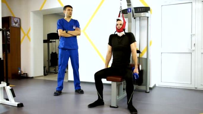 英俊的男人在健身房和教练一起在健身器材上伸展脊柱。高清