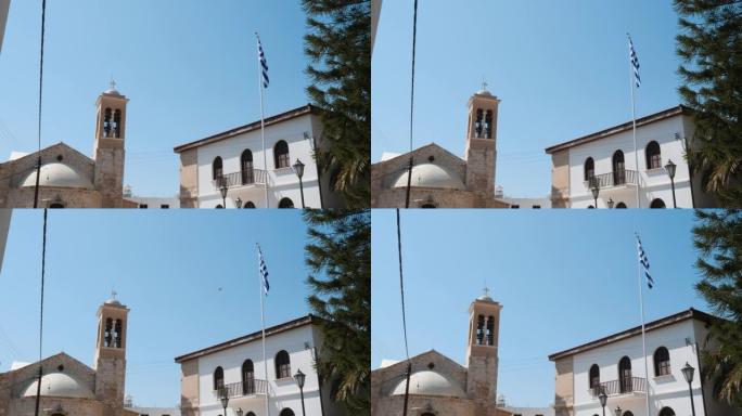 高旗旗杆上的希腊国旗的美丽景色，背景是教堂