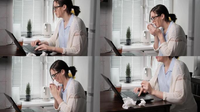 生病的女孩自由职业者在工作概念。年轻时候戴眼镜的迷人女孩在笔记本电脑键盘上打字，用纸手帕打破和吹鼻子