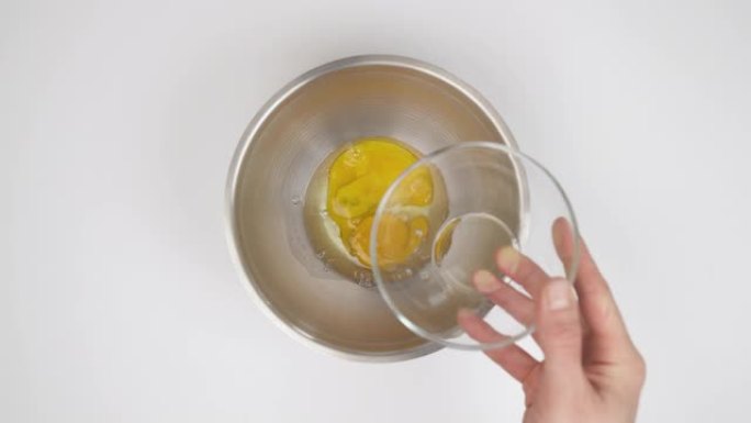 将生鲜鸡蛋倒入碗中的特写镜头-俯视图。准备配料概念