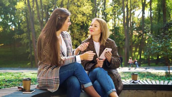 时尚女孩在公园使用智能手机在社交媒体上观看照片
