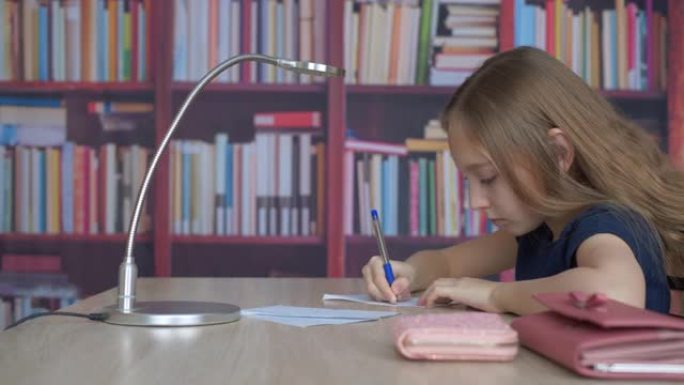学生女生用笔在书柜背景纸上写字。少女少女在家庭办公室做家庭作业，背景在图书馆的书架上。