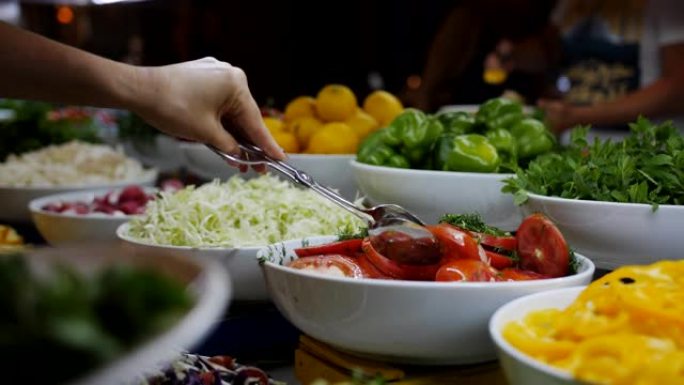 特写女人把一盘西红柿和辣椒从自助餐里放在餐厅里，特写镜头。