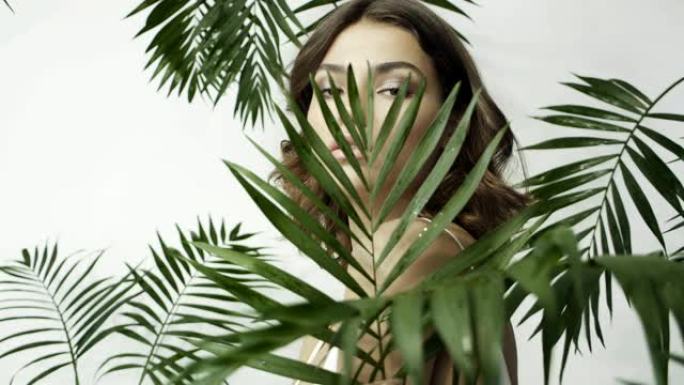 热带植物中晒黑的女孩。棕榈叶。