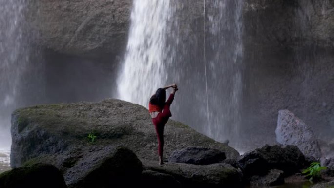 亚洲女子在瀑布练习或做瑜伽。美丽的风景，自然的背景，泰国。女性专业瑜伽