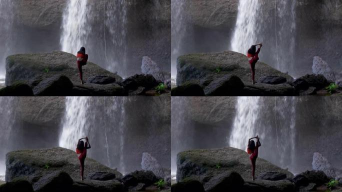 亚洲女子在瀑布练习或做瑜伽。美丽的风景，自然的背景，泰国。女性专业瑜伽