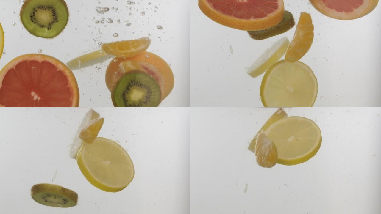 慢动作。新鲜切片的水果落入水中，白色背景上有飞溅和气泡。