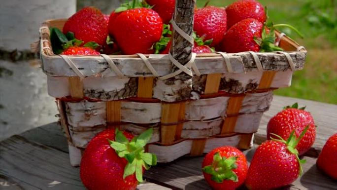 户外木桌上篮子里成熟的红草莓全景