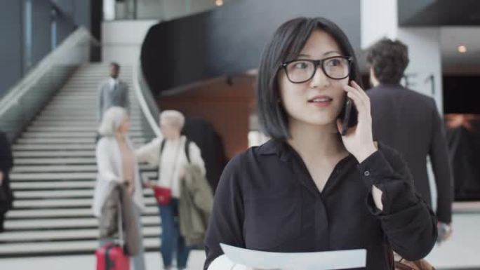 带着登机牌微笑的中国女子在机场通过电话聊天