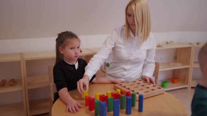 学龄前老师向女孩解释如何玩玩具积木游戏