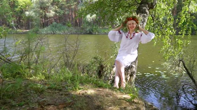 穿着乌克兰民族服装的漂亮女人靠在河边的桦树上