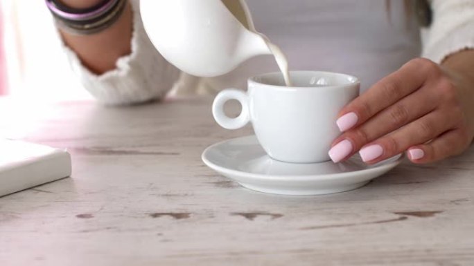 无法辨认的年轻女子在咖啡中倒牛奶的中段