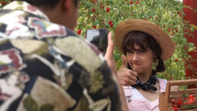 年轻夫妇农民情人一起自拍，在奥加尼奇农场展示一篮子西红柿，转基因食品，生物食品，另类ifestyle