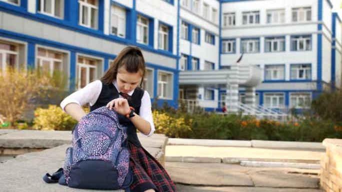 妈妈走过去亲吻大学附近的少女。学生女生坐在学院的院子里，正在背包里找东西。