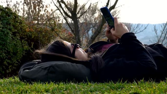 躺在草地上的年轻女子和短信