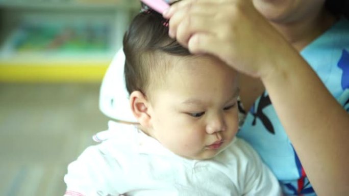 母亲为婴儿梳理健康的头发