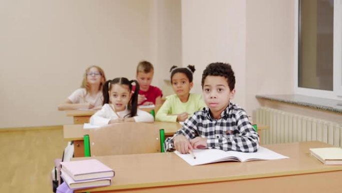 多种族儿童在教室里举手。