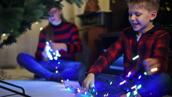 小男孩和他的妹妹在圣诞树上准备圣诞灯