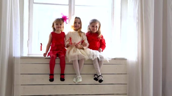 三个小女孩坐在白色的窗户上