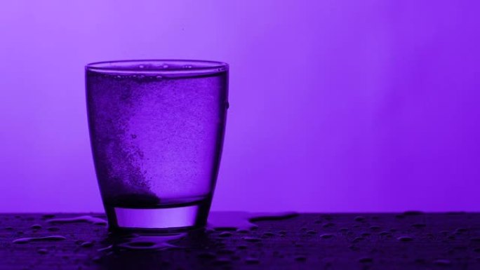 泡腾片滴入一杯水-紫色背景，慢动作