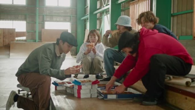 年轻的日本滑板手在滑板会议上吃披萨