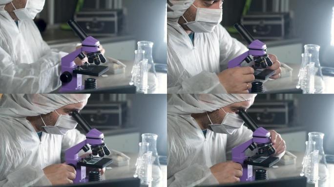 实验室里戴着防护面罩的科学家看着显微镜。