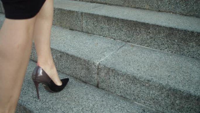 特写女人的腿在街上走上楼。穿着黑色鞋子走路的女人