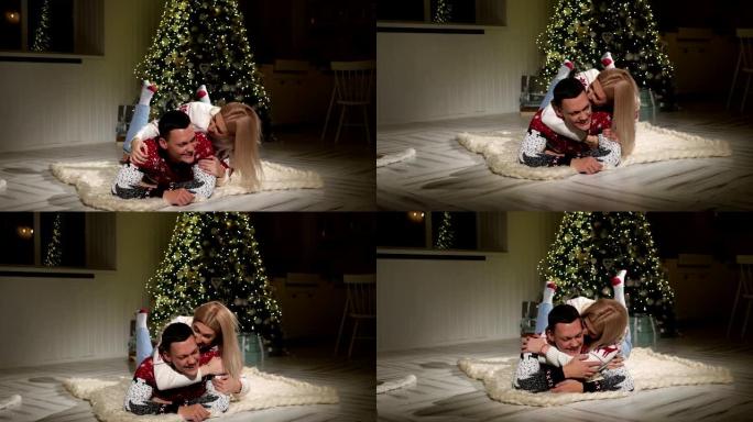 穿着圣诞毛衣的快乐夫妇躺在地板上大笑。