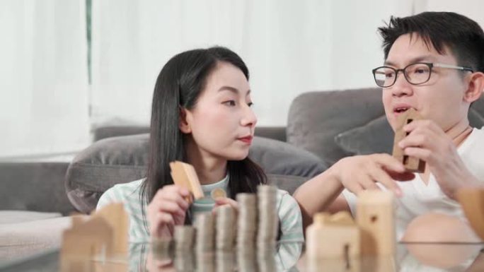年轻迷人的亚洲男女夫妇专注于集中资金储蓄和投资关注家庭金融理念概念手计数硬币堆堆栈和房屋模型
