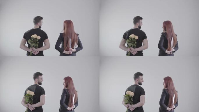 黑发男人和红发女人看着对方，微笑着站在白色背景下。男孩拿着一束黄玫瑰，女孩手里拿着大刀。婚姻，关系