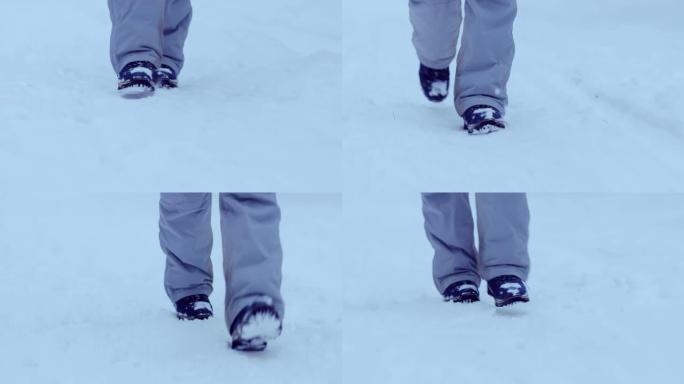 穿着冬靴的腿走在雪道上。冬走，踏雪。特写。