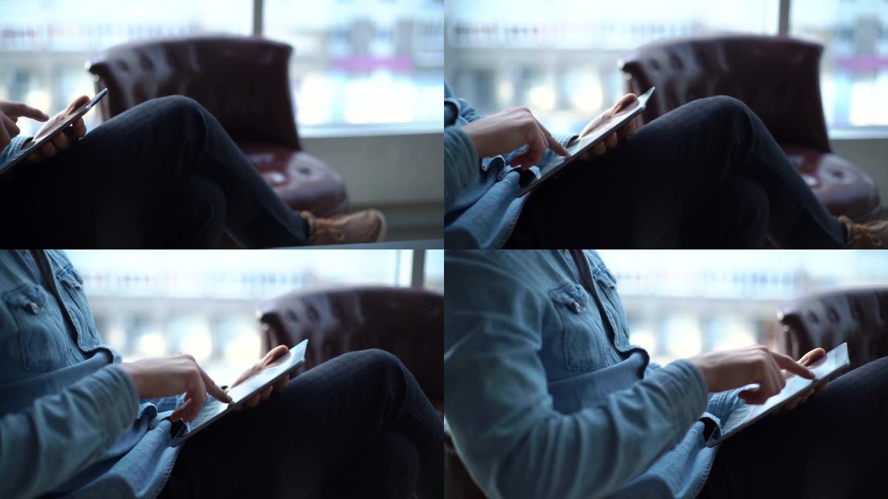 一个yuoung商人使用平板电脑坐在办公室的椅子上的特写镜头。