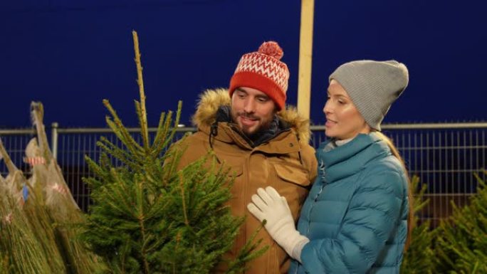 幸福的夫妇在市场上购买圣诞树