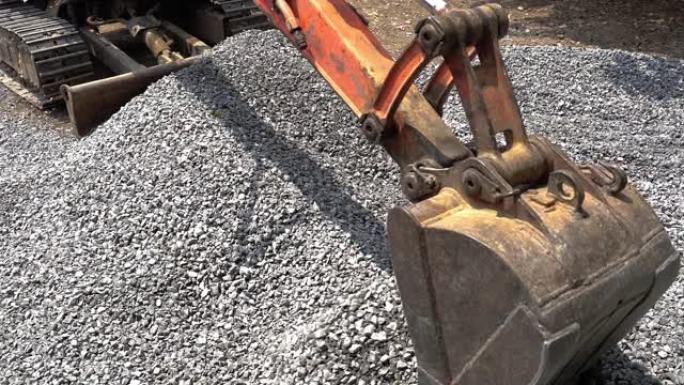 挖掘机正在挖掘石头，用于农村地区的道路建设或修复背景。