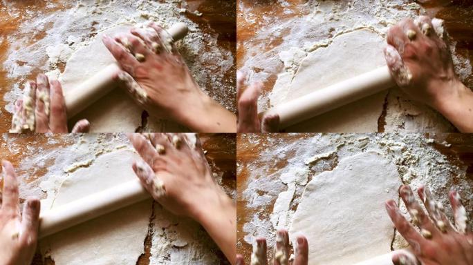 女性用rolling面杖将面团铺在一块用面粉弄脏的木板上