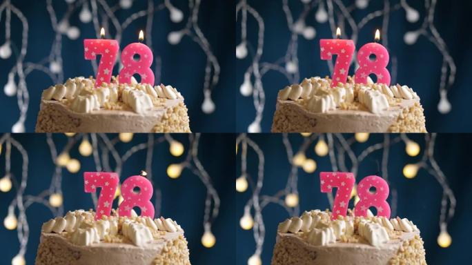 蓝色背景上有78号粉色蜡烛的生日蛋糕。蜡烛吹灭了。慢动作和特写视图