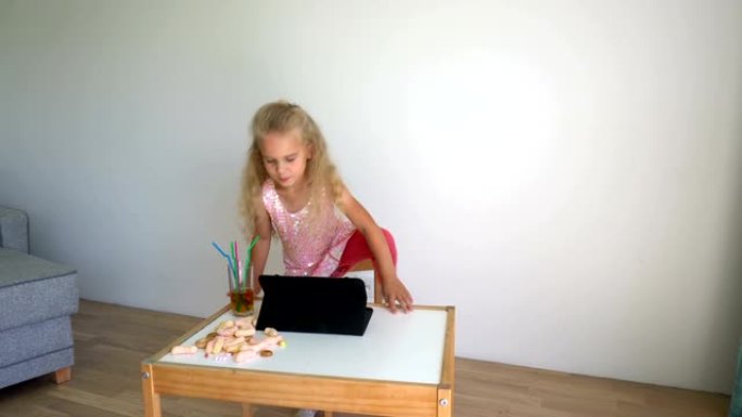 活跃的女童在平板电脑上打开音乐，在椅子上跳舞。万向节运动