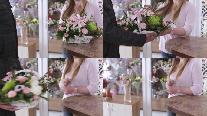 女花店给男买家一个白色的篮子，上面放着一束美丽的鲜花。卖花，卖花生意，买礼物。