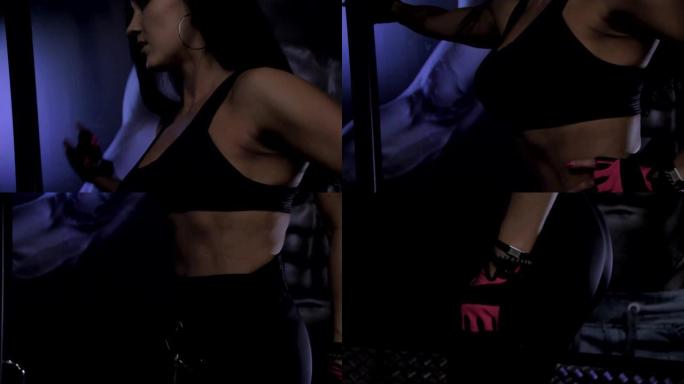 身材好的女孩在健身房里与黑暗的背景和光线合影