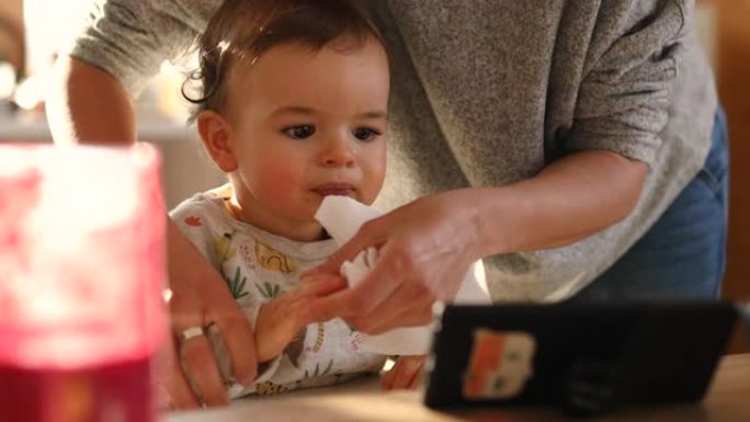 可爱的男婴看手机卡通片咬手指