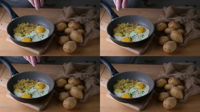 平底锅里的煎蛋和瑞士鱼肉是用新鲜的细香葱在木制厨房桌子上调味的，上面放着一袋土豆，慢动作