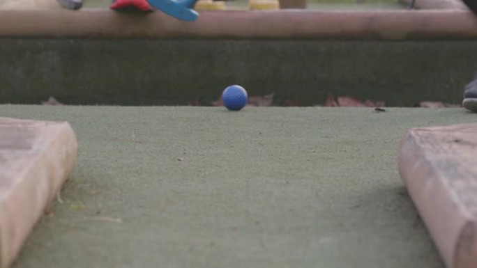 儿童用推杆在迷你高尔夫球场上击打彩色高尔夫球
